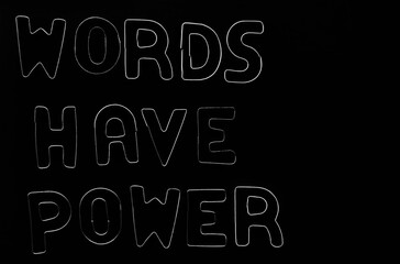 Words have power, silver text made from iron, metal letters. isolated on black background. Phrase words have power on the table. Blocks of alphabet letters on  backdrop.