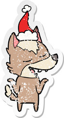 hand drawn distressed sticker cartoon of a wolf laughing wearing santa hat