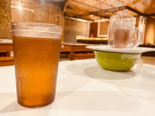Photo of a glass of warm or cold tea on the table at a restaurant with bowl and plate behind bright