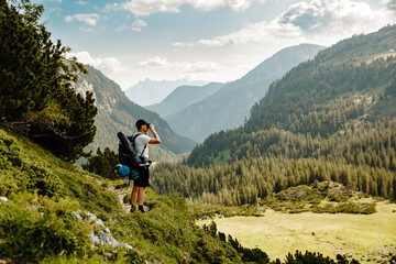 Naklejka na ściany i meble Hiking man on a hiking path in Switzerland Alps overlooks the horizon