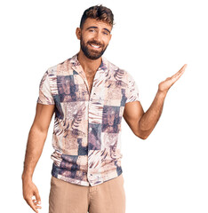 Young hispanic man wearing summer clothes smiling cheerful presenting and pointing with palm of...