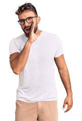 Young hispanic man wearing casual clothes and glasses hand on mouth telling secret rumor, whispering malicious talk conversation