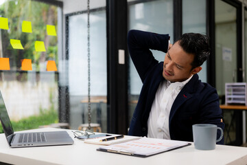 Businessman raises arms while tired and shoulder pain from office syndrome. Office worker,...