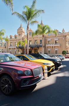 Monaco, Monte-Carlo, 21 October 2022: Square Casino Monte-Carlo at sunny day, a lot of luxury cars, Hotel de Paris, wealth life, tourists take pictures of the landmark, pine trees, blue sky, flowers