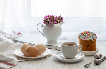 Easter still life with painted eggs, Easter cake and tea in a cup on the windowsill on a sunny day