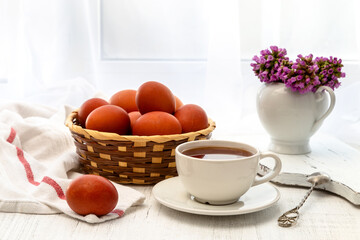 Easter still life with painted eggs, Easter cake and tea in a cup on the windowsill on a sunny day