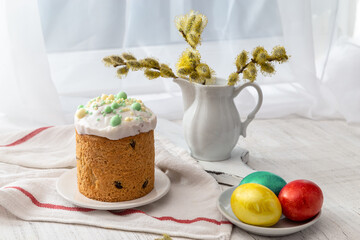 Easter still life with colored eggs, Easter cake and willow in a milk jug on the windowsill on a...