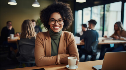 Smiling businesswoman working on a laptop in her office and looking to the camera