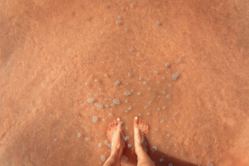 Female legs against the background of a sandy pink beach