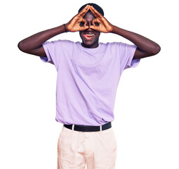 Fototapeta premium Young african american man wearing casual clothes doing ok gesture like binoculars sticking tongue out, eyes looking through fingers. crazy expression.