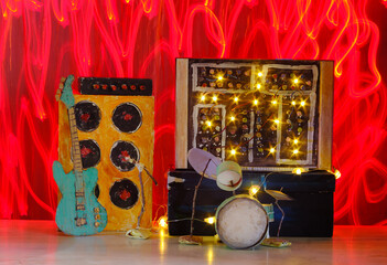 Grungy cardboard models of synthesizer,drum kit,guitar,amplifier and microphone on stage with wild light trails,music,performance,instruments concept,free copy space
