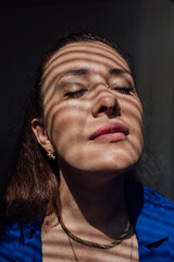 Beautiful brunette woman and light and shadow from window blinds