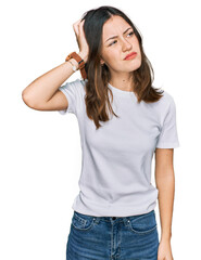 Young beautiful woman wearing casual white t shirt confuse and wondering about question. uncertain with doubt, thinking with hand on head. pensive concept.
