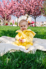 a smiling baby is sitting on a blanket under blooming cherry trees