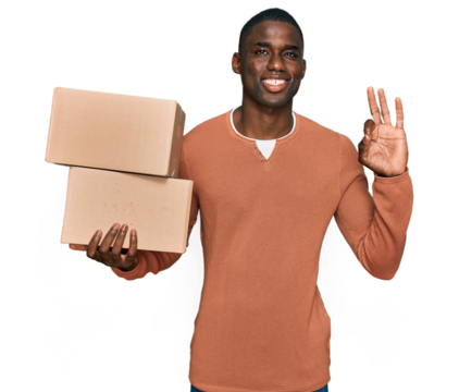 Young african american man holding delivery package doing ok sign with fingers, smiling friendly gesturing excellent symbol