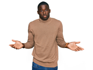 Young african american man wearing casual winter sweater clueless and confused expression with arms and hands raised. doubt concept.