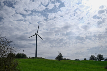 Wind turbines on green meadow with cloudy sky