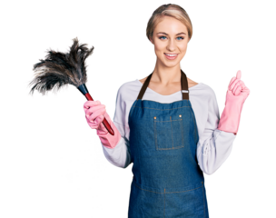 Beautiful young blonde woman wearing apron holding cleaning duster cheerful with a smile on face pointing with hand and finger up to the side with happy and natural expression
