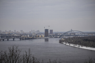 Naklejka premium KYIV, UKRAINE - DECEMBER 6, 2023: A SNOW-COVERED CITY WITH A WONDERFUL VIEW OF THE DNIPRO RIVER AND PODIL. FOG COVERS THE CITY AND MINUS TEMPERATURE OUTSIDE