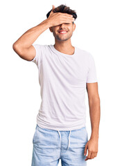 Young hispanic man wearing casual clothes smiling and laughing with hand on face covering eyes for surprise. blind concept.