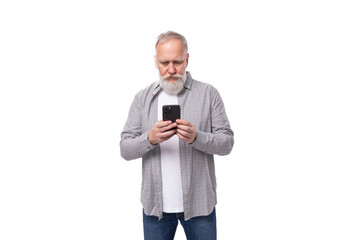 a handsome pensioner man with a beard and a big mustache is dressed in a shirt and jeans chatting on the phone
