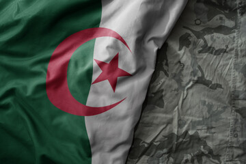 waving flag of algeria on the old khaki texture background. military concept.