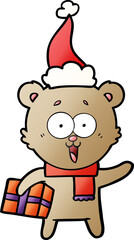 laughing teddy  bear with christmas present wearing santa hat
