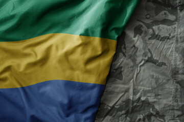 waving flag of gabon on the old khaki texture background. military concept.