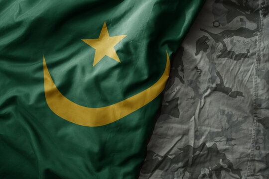 waving flag of mauritania on the old khaki texture background. military concept.