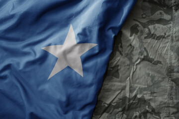 waving flag of somalia on the old khaki texture background. military concept.