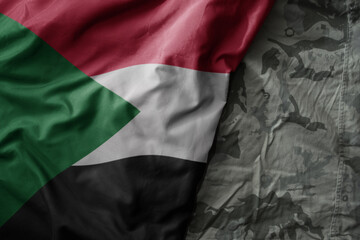 waving flag of sudan on the old khaki texture background. military concept.