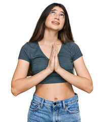Young beautiful teen girl wearing casual crop top t shirt begging and praying with hands together...