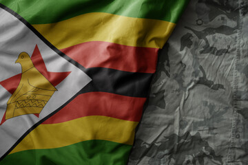 waving flag of zimbabwe on the old khaki texture background. military concept.