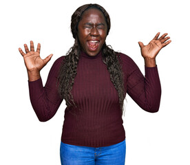 Young african woman wearing casual winter sweater celebrating mad and crazy for success with arms...