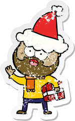 hand drawn distressed sticker cartoon of a bearded man with present wearing santa hat