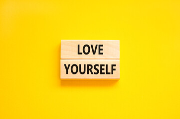 Love yourself symbol. Concept words Love yourself on beautiful wooden blocks. Beautiful yellow table yellow background. Psychology love yourself concept. Copy space.