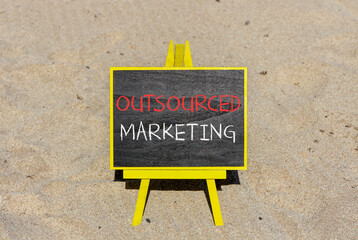 Outsourced marketing symbol. Concept words Outsourced marketing on beautiful black chalk blackboard. Beautiful sand sea beach background. Business Outsourced marketing concept. Copy space.