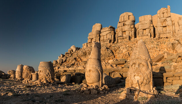 Statue heads with headless seated statues at sunrise, East Terrace, Mount Nemrut, Turkey
