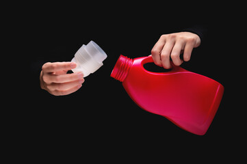 woman's hand pours cleaning product or bleach on a black background. Woman opened detergent,...