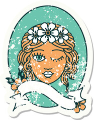 worn old sticker with banner of a maiden with crown of flowers winking