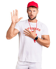 Young caucasian man wearing lifeguard t shirt holding whistle swearing with hand on chest and open...