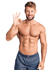 Fototapeta premium Young caucasian man standing shirtless showing and pointing up with fingers number three while smiling confident and happy.