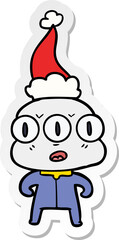hand drawn sticker cartoon of a three eyed alien wearing santa hat