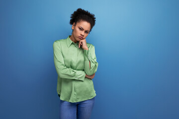 young brunette hispanic woman with curly hair dressed in a green blouse on a background with copy space. people lifestyle concept