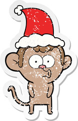 hand drawn distressed sticker cartoon of a hooting monkey wearing santa hat