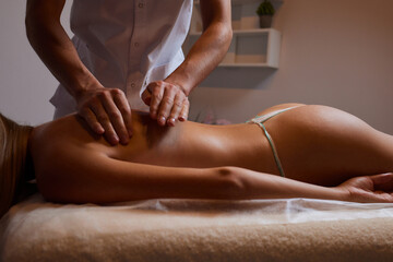 Body massage treatment. Woman having massage in the spa salon. Masseur working on his back.