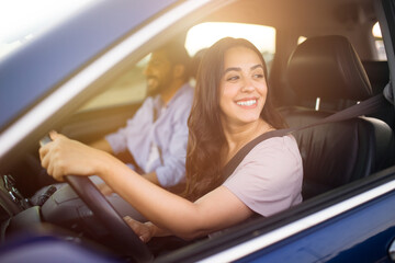 Fototapeta na wymiar Smiling middle eastern woman driving with partner in passenger seat