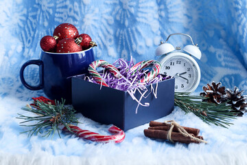 New Year's background: red mug with caramel, box with gifts, clock, pine checkers on a blue background