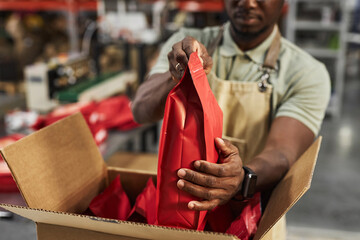 Close up of Black young man carefully putting coffee bags in cardboard box at packaging and...