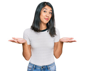 Beautiful asian young woman wearing casual white t shirt clueless and confused expression with arms...